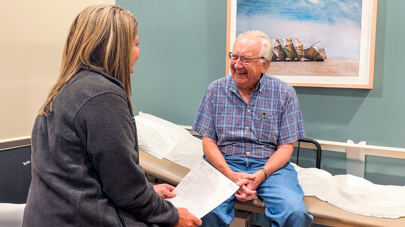 A provider speaking with an elderly patient in an exam room